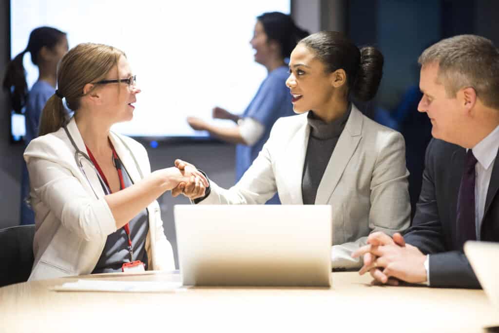 A physician meeting with two executives from an ACO about risk adjustment and care gaps.