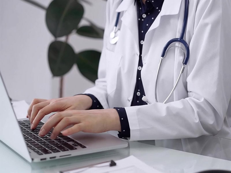 Female physician typing on a keyboard, representing the importance of providers using heath IT in value-base care programs.