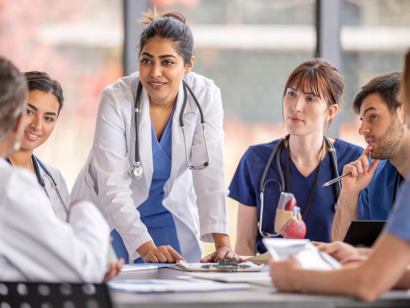 A group of healthcare providers sitting around a table discussing how to set clear goals for value based care in their organization.